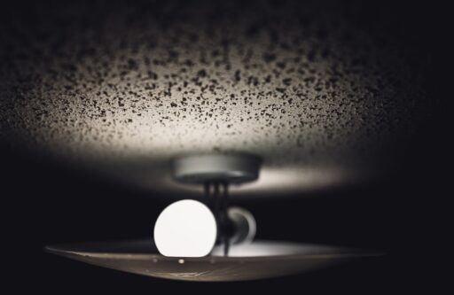 Aged look of popcorn textured white ceiling and a dual light fixture and glass cover | does popcorn ceiling have asbestos