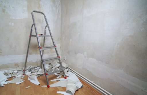A ladder, near a wall stripped off of old wallpaper | professional wall removal